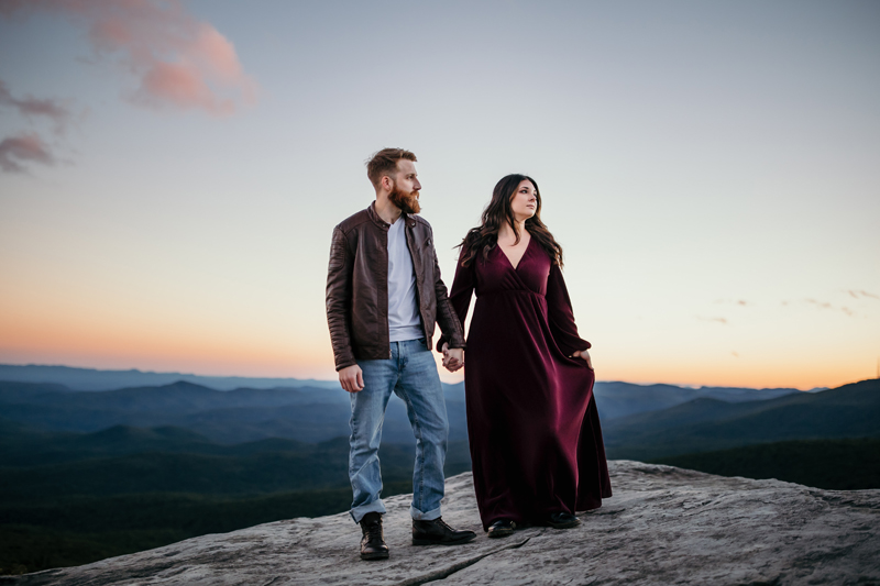 Family Photographer, man and woman hold hands on mountain boulder at sunset